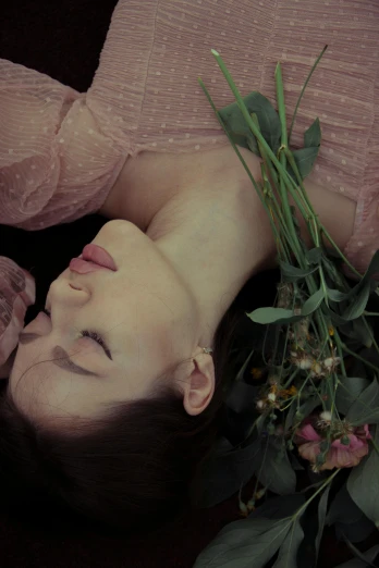 a beautiful young lady laying next to a bouquet of flowers