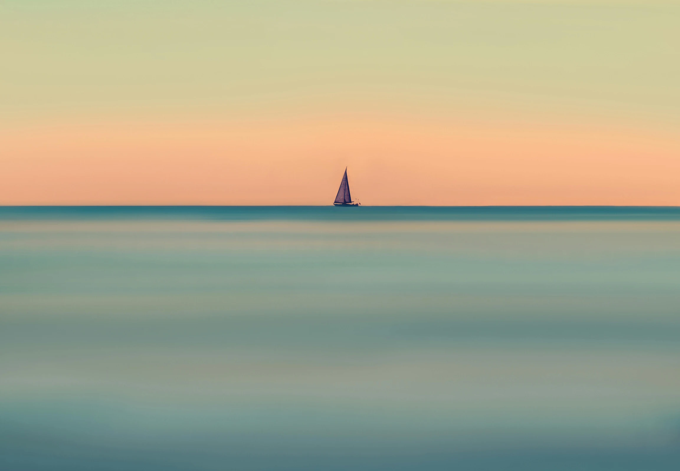 a single sailboat is on the water at sunset