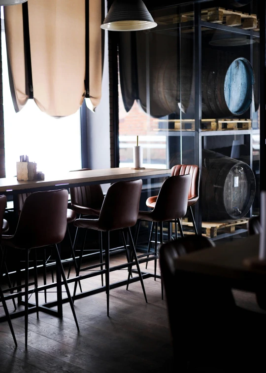 a bar with chairs and wine glasses behind it