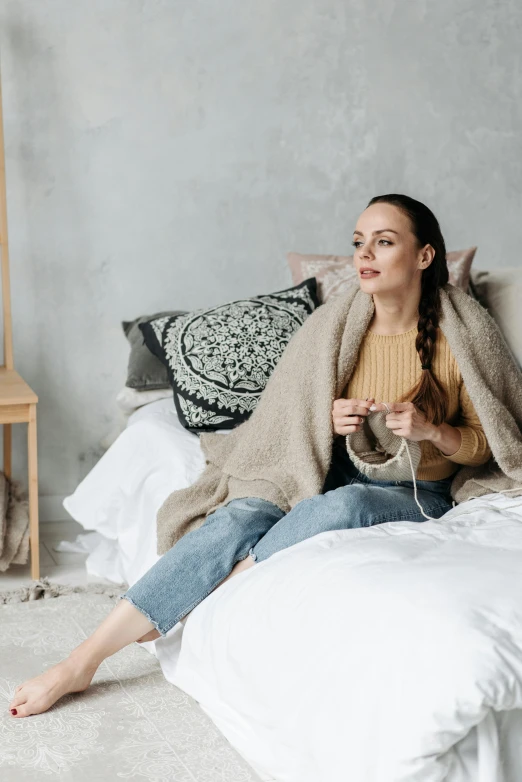 a woman in jeans and a yellow top is sitting on a bed