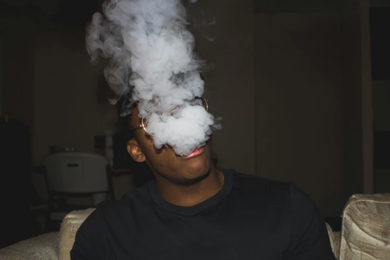 a man in a black shirt smoking a white cloud