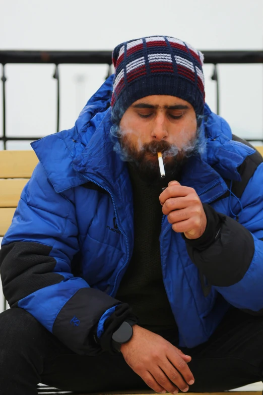 a man sits on a bench smoking a cigarette