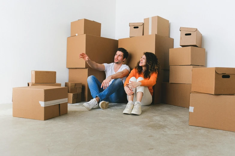 two people sitting on a floor surrounded by cardboard boxes