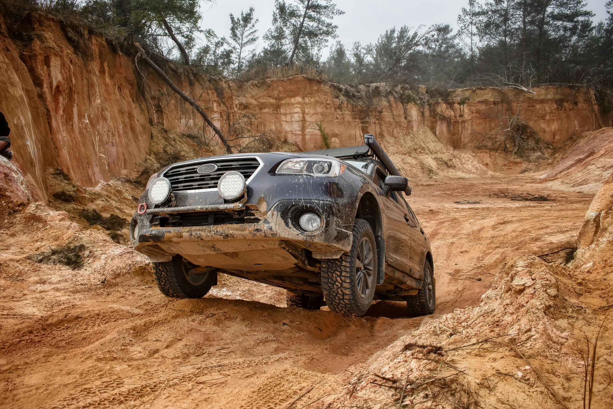 the car is stuck in the dirt, but there are other cars sitting in the dirt