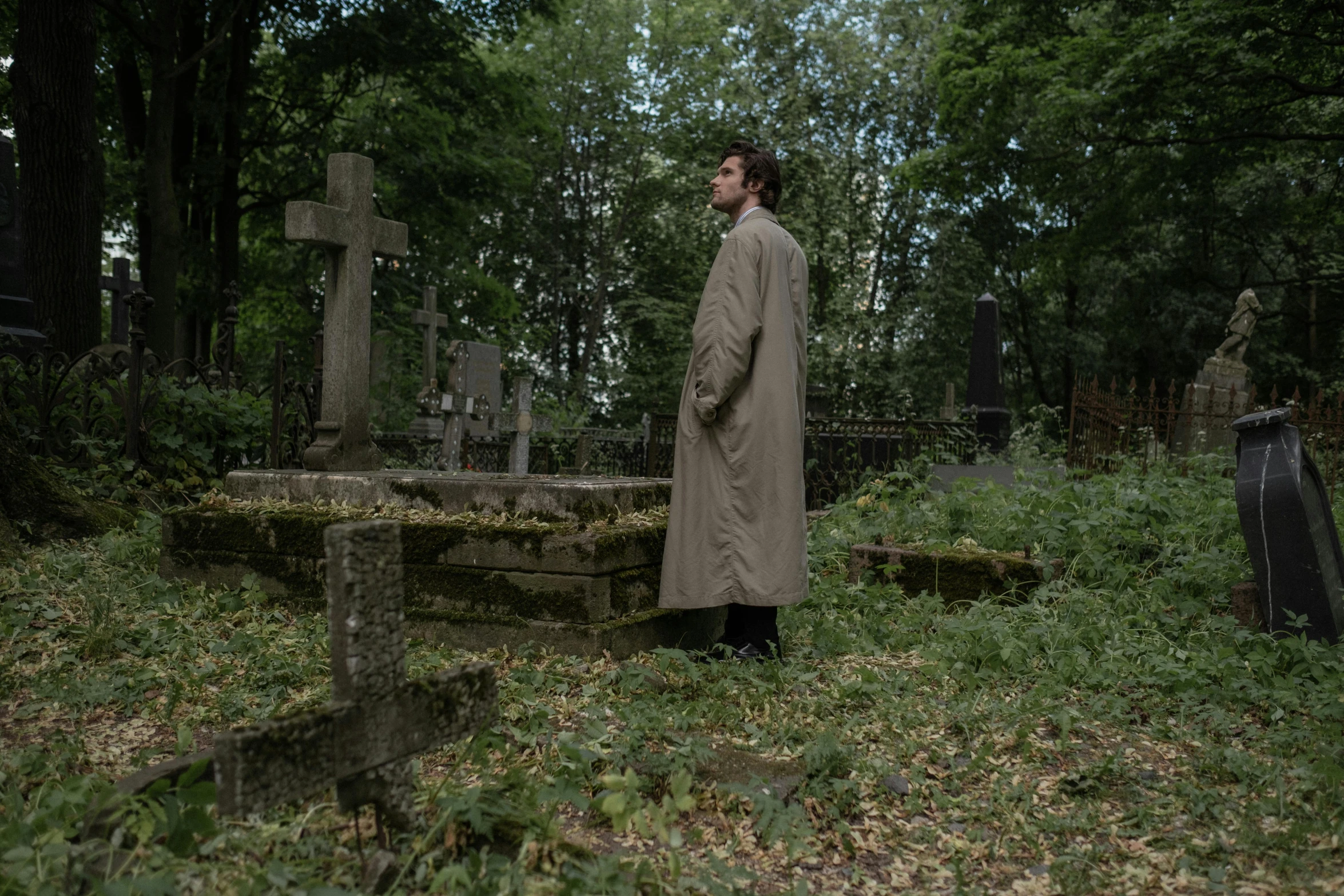 a man stands in the woods in front of some graves