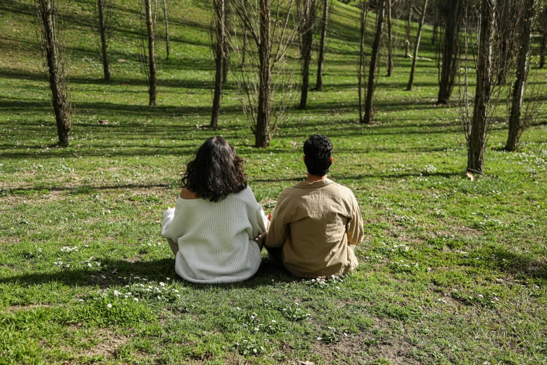 there are two people sitting on the ground in the grass