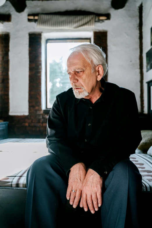 an old man sitting in front of a bed