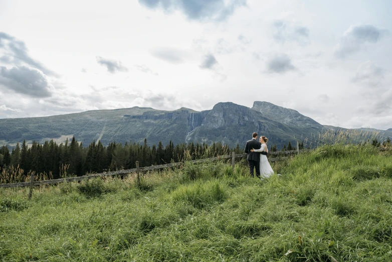 a newly married couple emce on a mountaintop with mountains in the distance