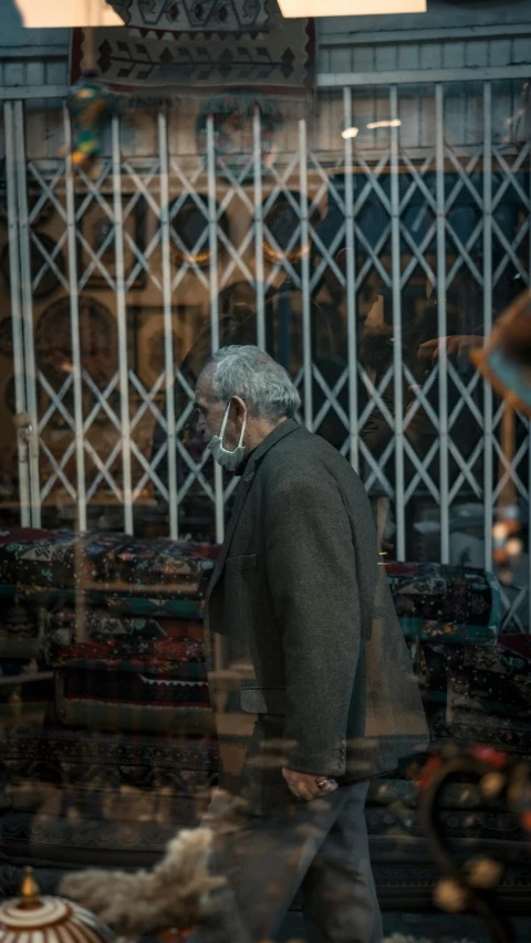 man walking past shop windows with an unusual window display behind him