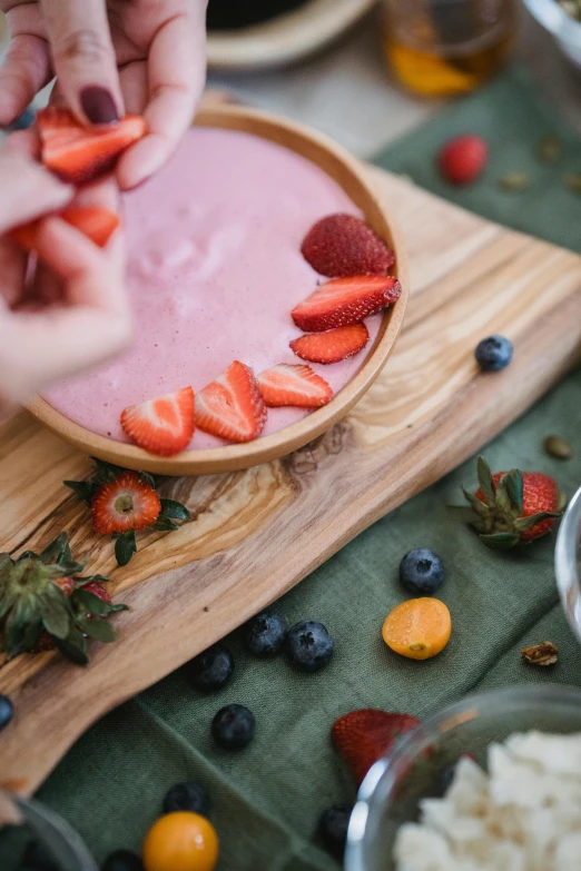 a bowl of fruit and someone placing it into it