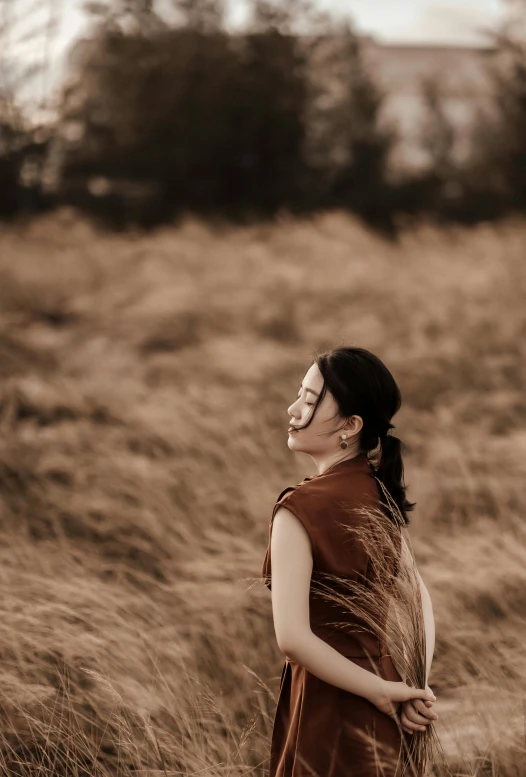 a woman standing in a field with grass behind her