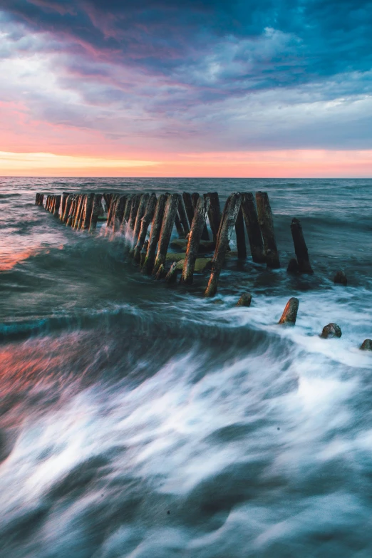 a long exposure po of water waves and wooden posts