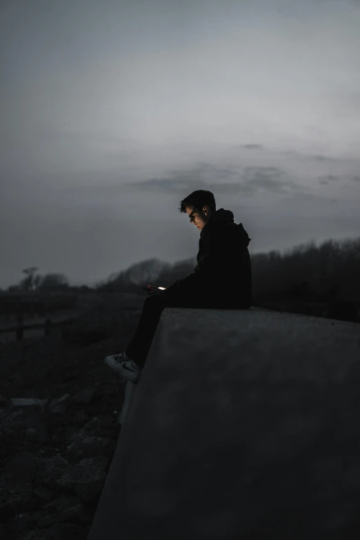 a person sitting on a wall with their cell phone in their hands