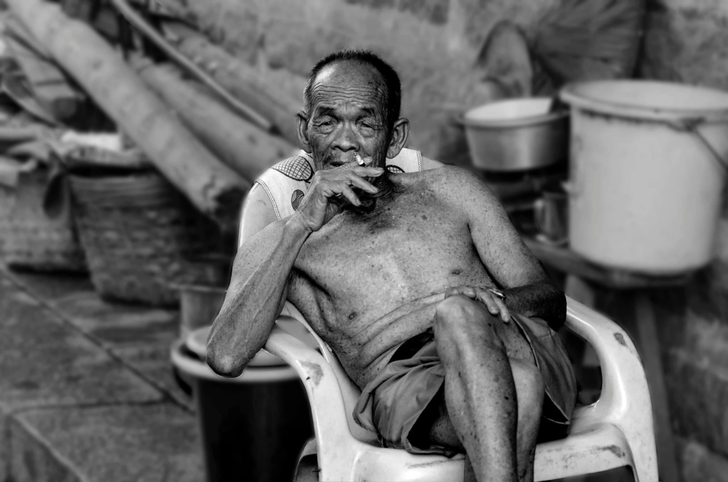 a man smoking on a white chair by a building