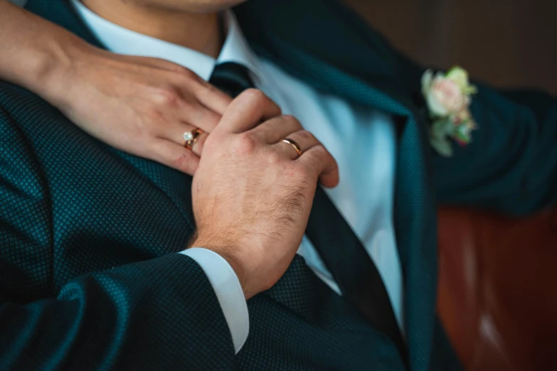 a close up of a person in a suit and tie adjusting his boutonniere