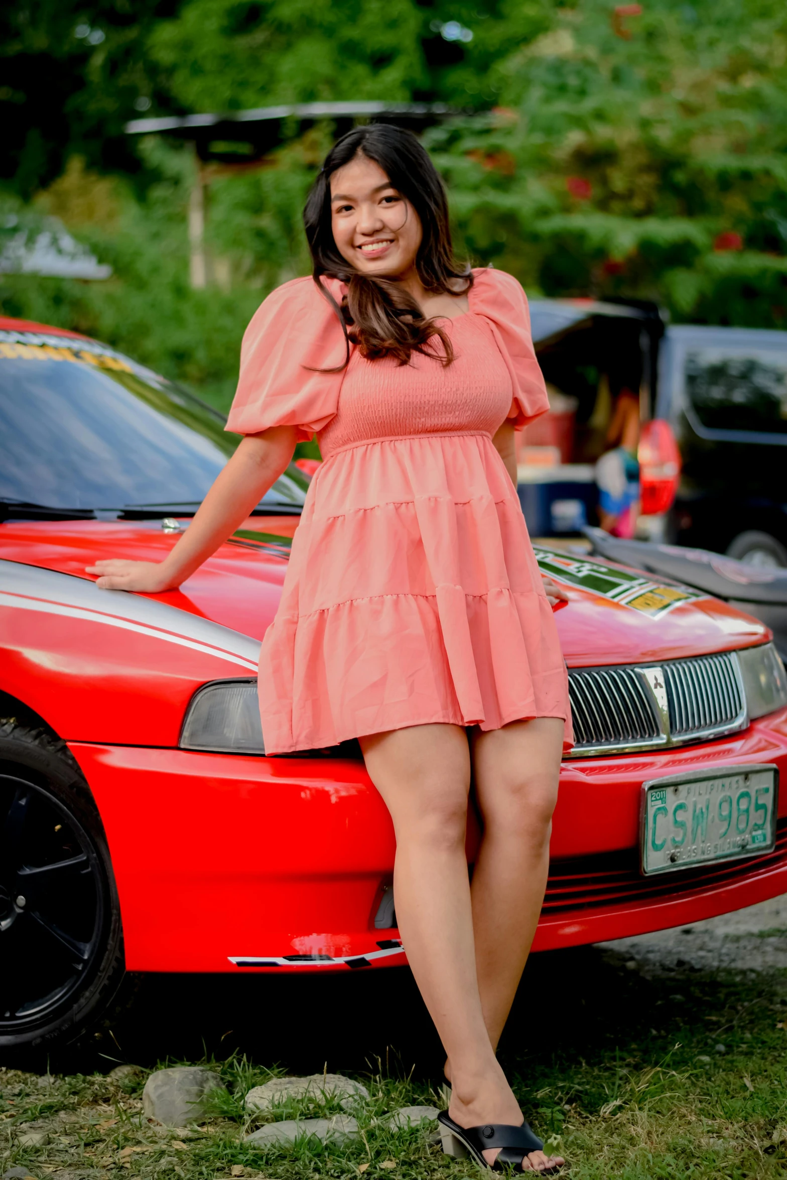 a woman posing with her car on the grass