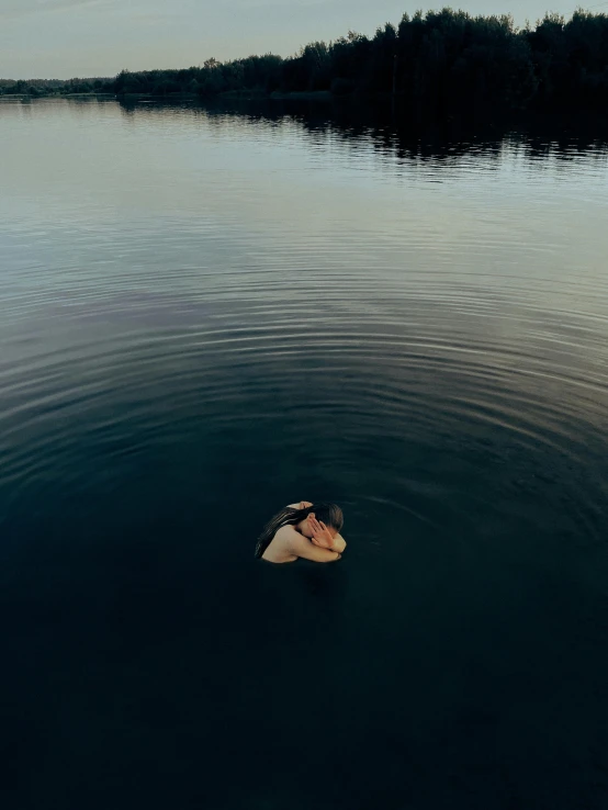 a woman is in a lake while floating on a sailboat