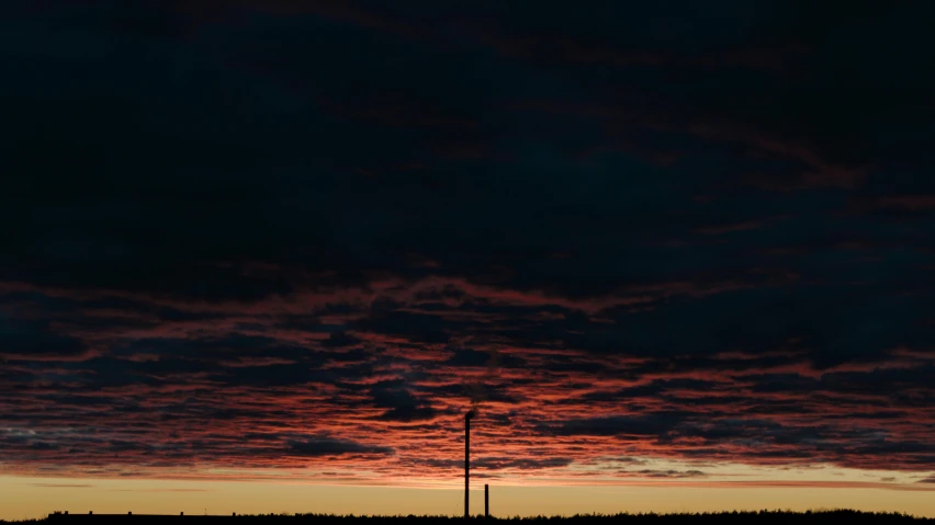 a cloudy sunset with a single light house