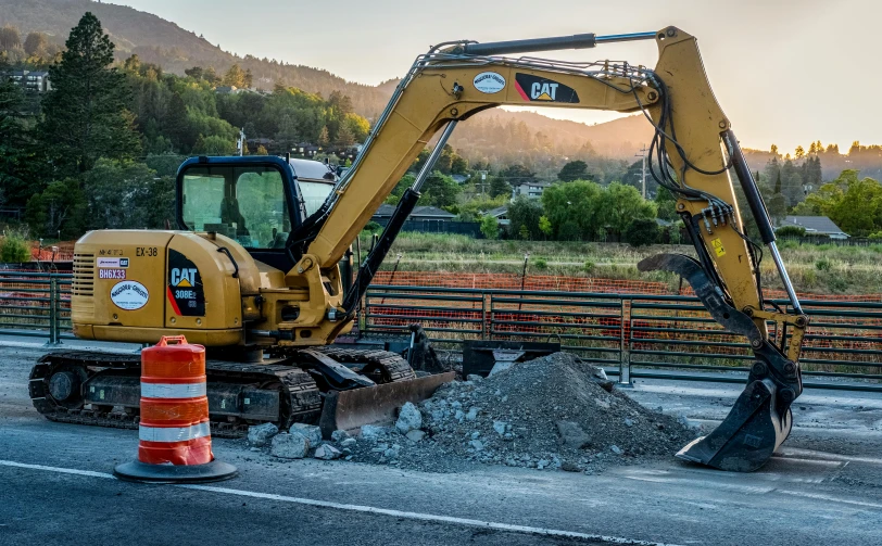 the excavator is parked beside the road in front of the road barrier