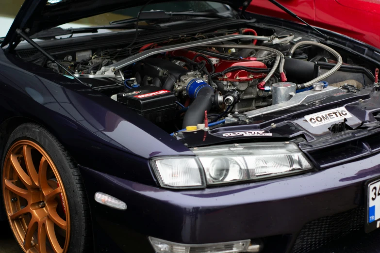 a car with the hood open and a red car below it