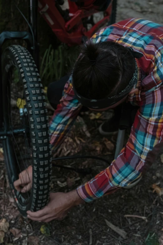 a man puts his bike tire onto the side of the tree