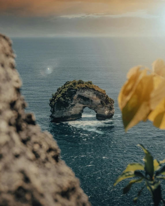 a lone rock sits on the water near a large body of water