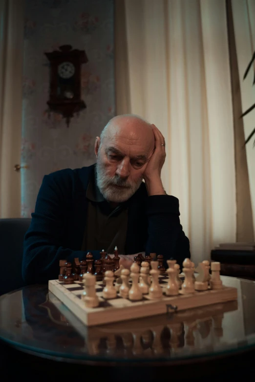 an old man is sitting at a chess table