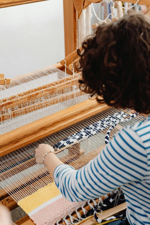 a woman working with weaving on a loom