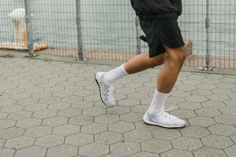 a man walking across the street wearing tennis shoes