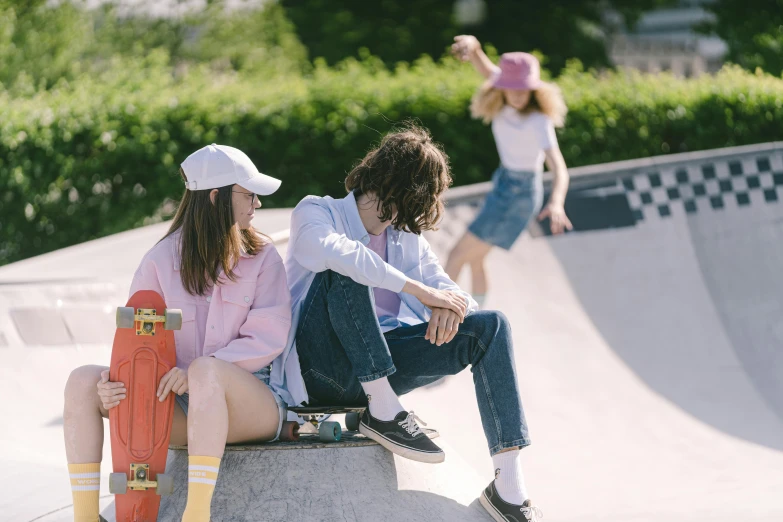 three children sitting together at the edge of a skate park