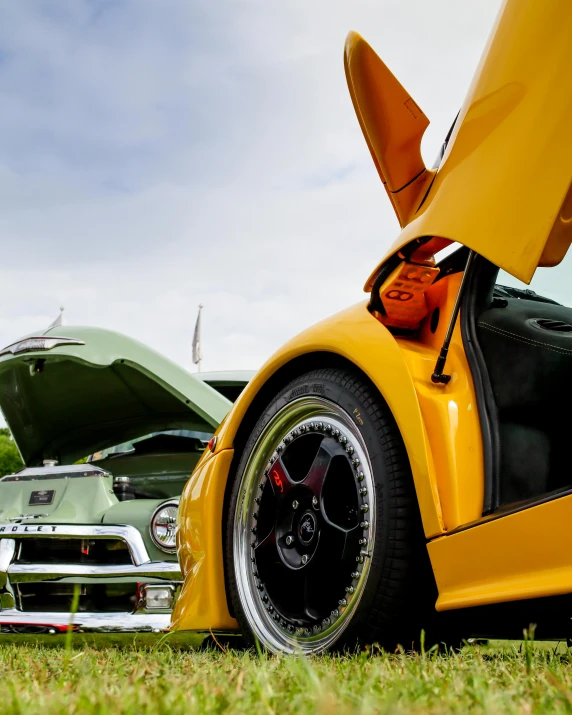 a yellow sports car parked next to another green car