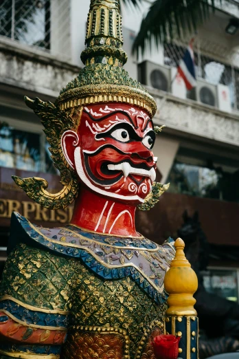 the large colorful statue is painted green, red, gold and white