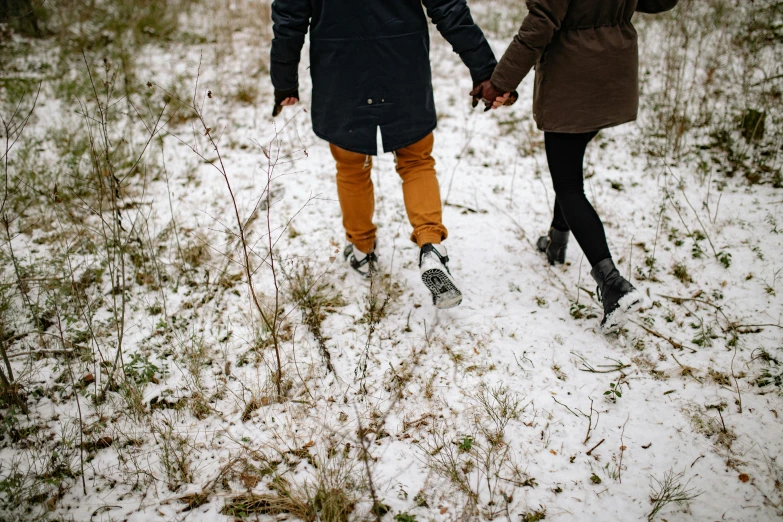 a couple walking through a snow covered forest