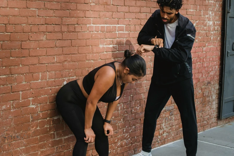 a man and woman standing against a brick wall