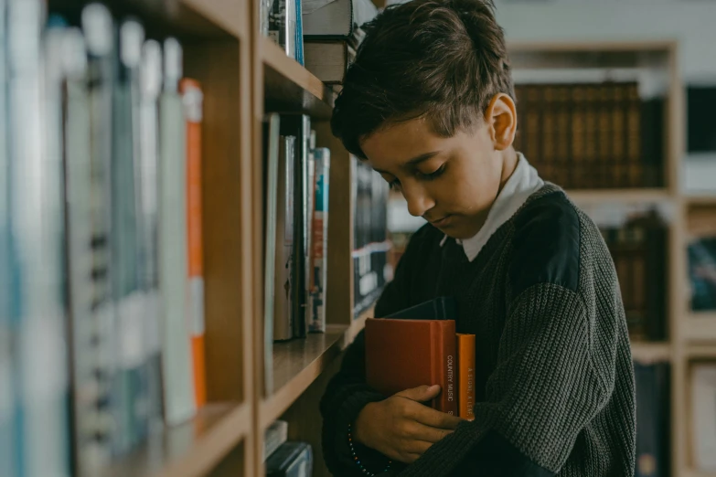 a boy reading a book at the liry