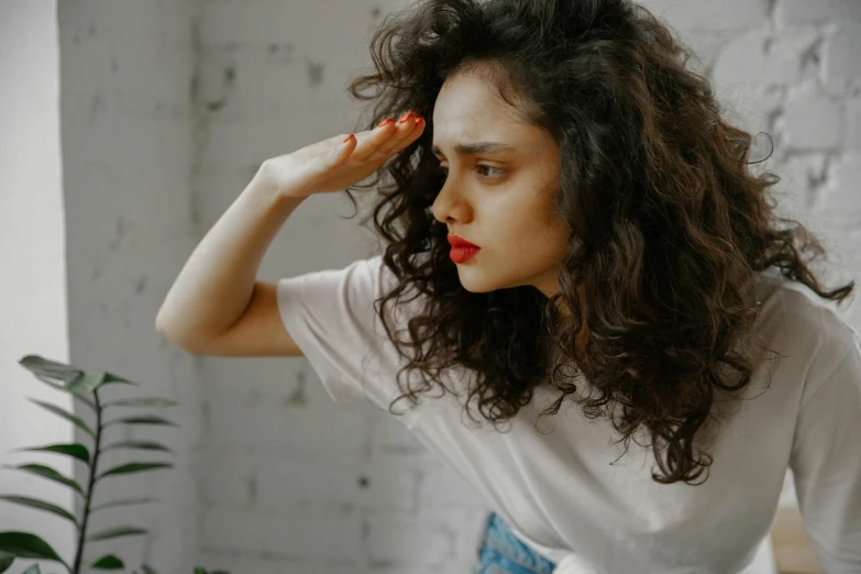 a woman looks over her shoulder and holds her head near her hand