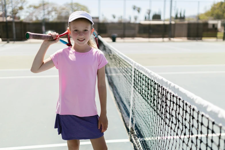 girl in a pink shirt and skirt holding tennis racket