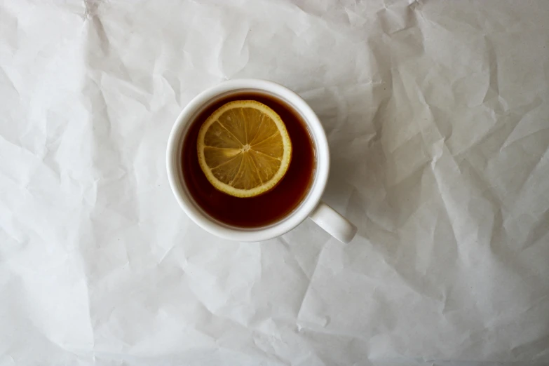 the top half of a cup filled with tea and half a lemon