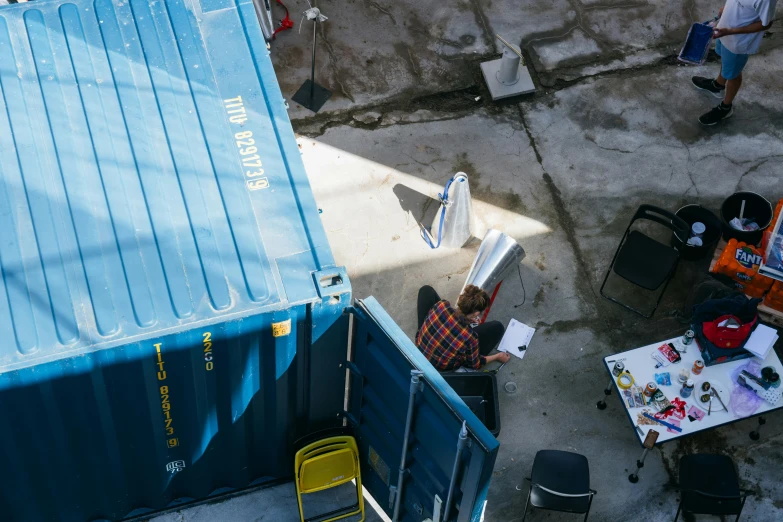 a man is sitting at a table near the blue container