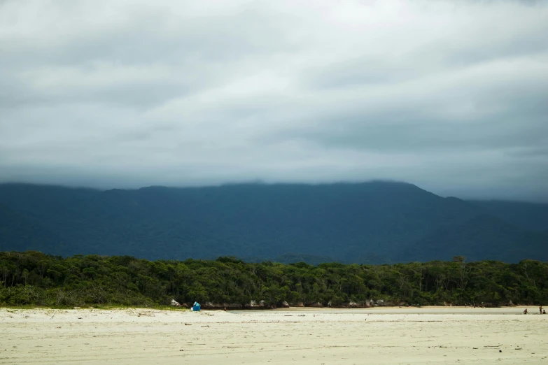 people fly kites on a beach near mountains