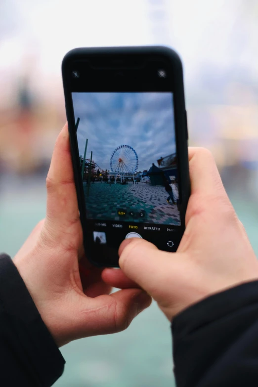 someone taking pictures of the ferris wheel from their smartphone