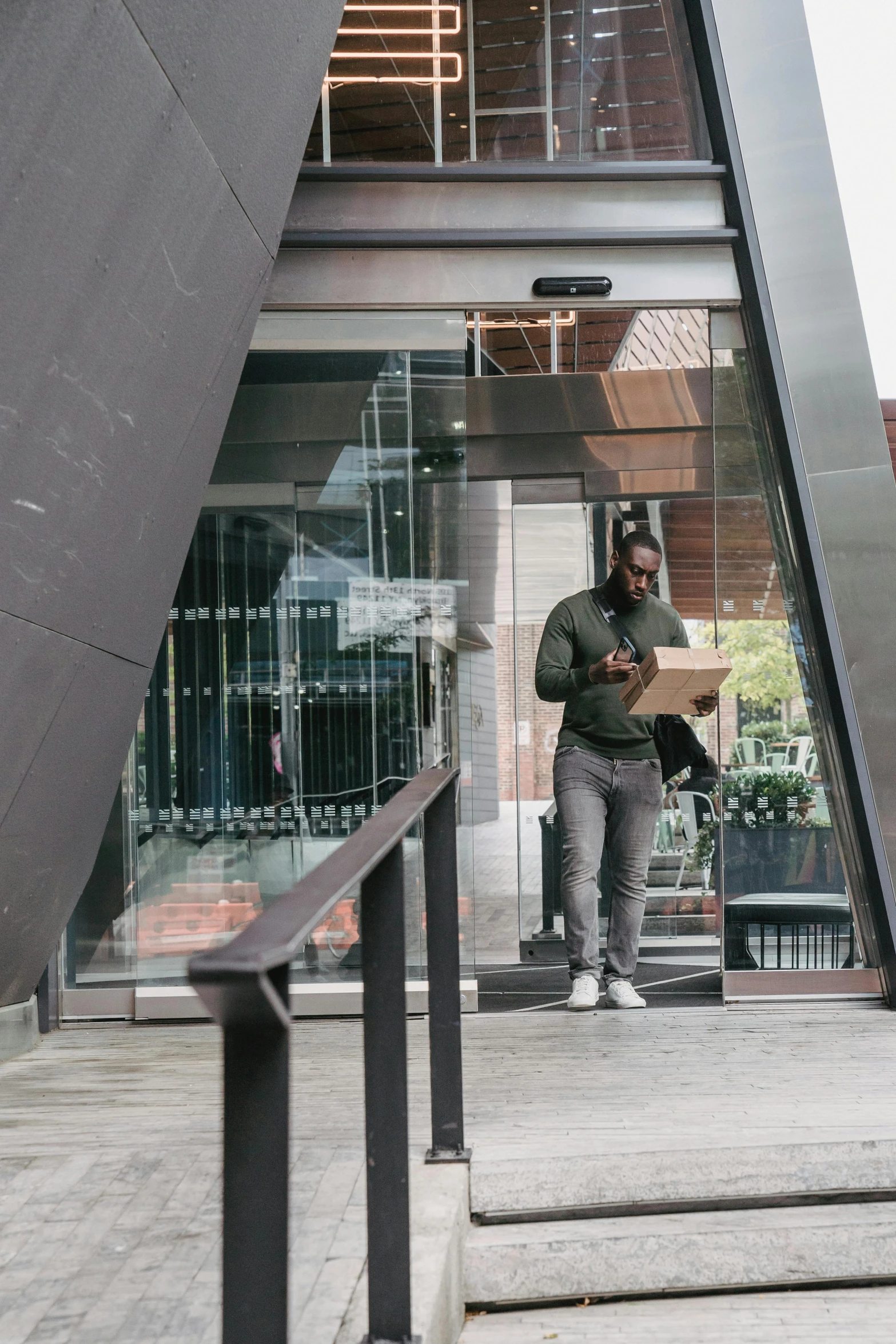 a man holding a cardboard box standing on the steps outside of a building