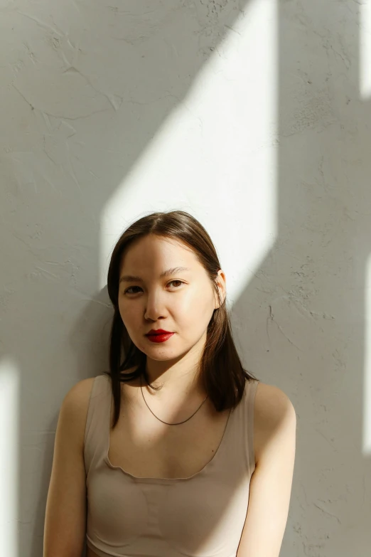 a woman standing next to a white wall