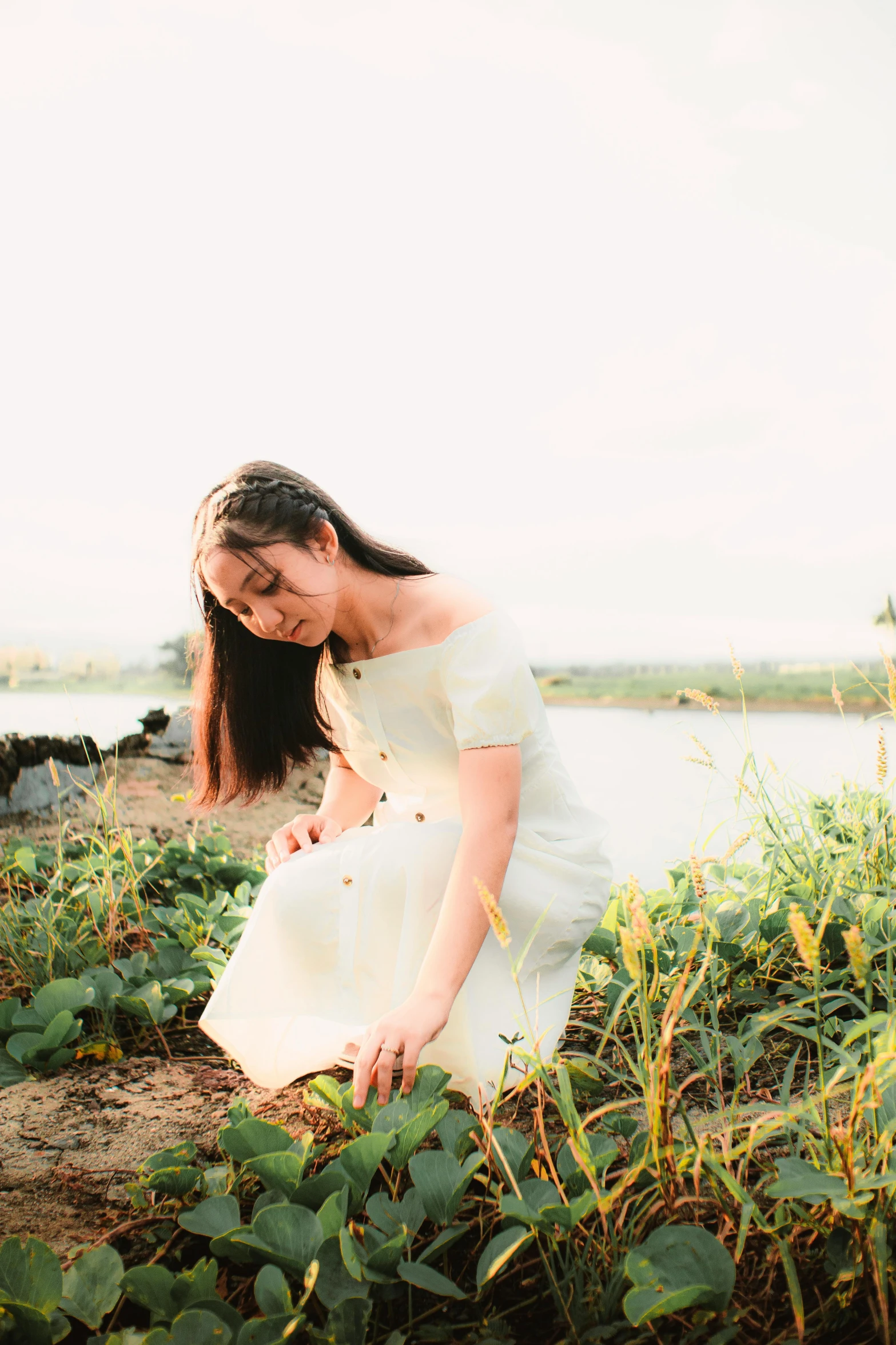 a woman kneeling down near some grass