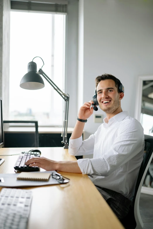 a man sitting at a desk talking on the phone