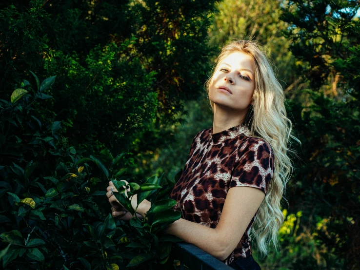 blonde hair woman looking upward while holding a flower