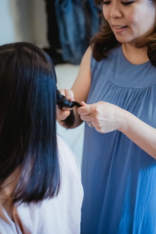 a woman is blow drying another girl's hair