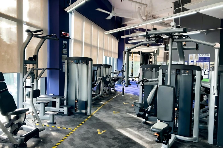 an empty gym with machines and people walking inside