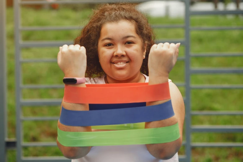 a smiling woman is holding up several colored bands