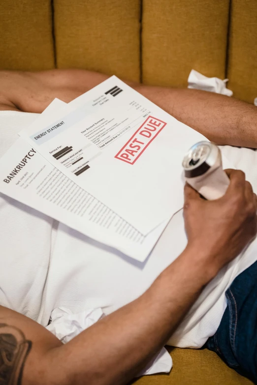 a man is sitting in a chair holding onto a paper and using an electronic device